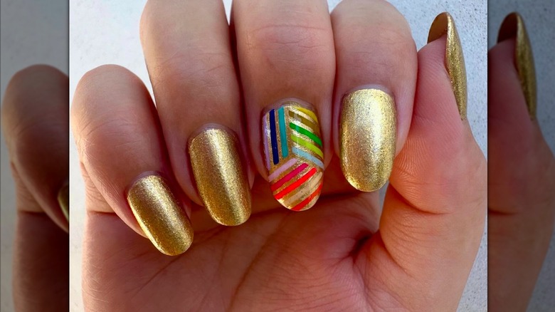 An art-deco manicure with gold nails and a rainbow accent nail