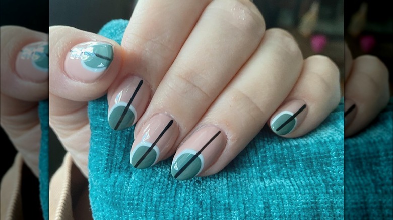 An art-deco manicure with green nails featuring black lines