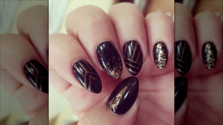 An art-deco manicure with black-and-gold nails and glitter