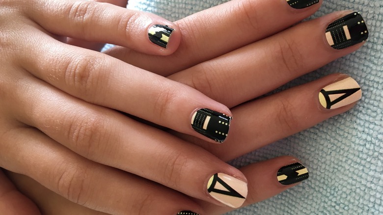 Two hands with a black-and-gold manicure