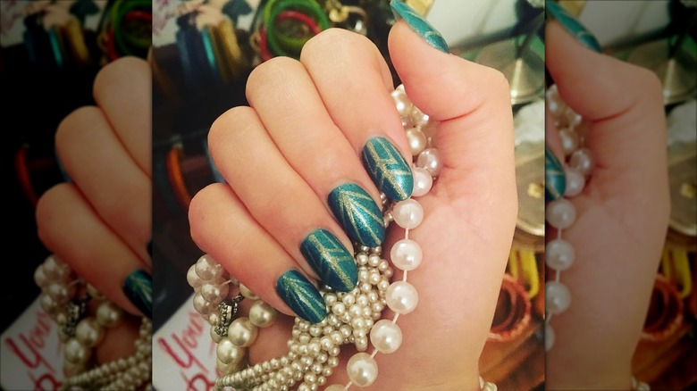 An art-deco manicure with green-and-gold nails
