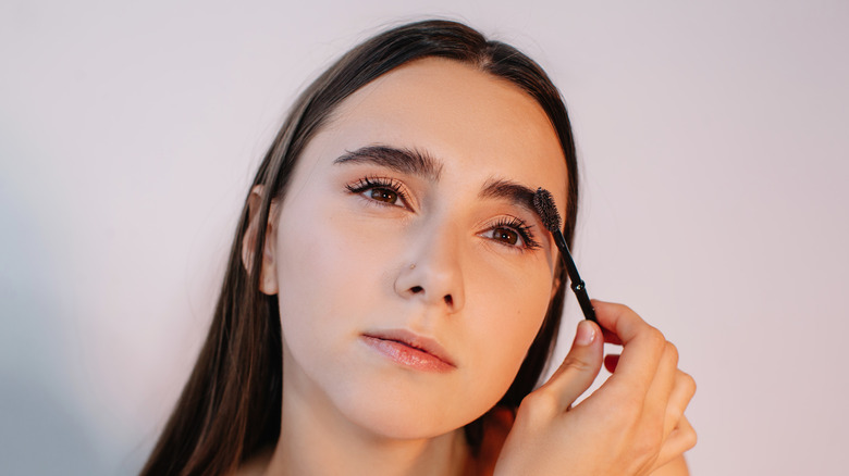 Woman with thick eyebrows using a spoolie