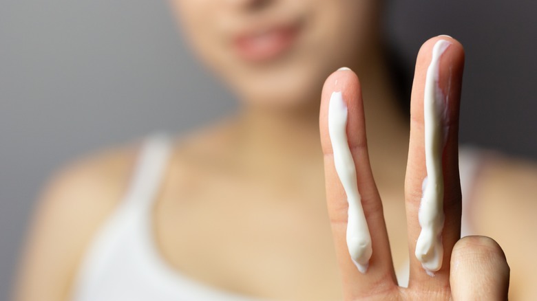 woman holding up two fingers with sunscreen