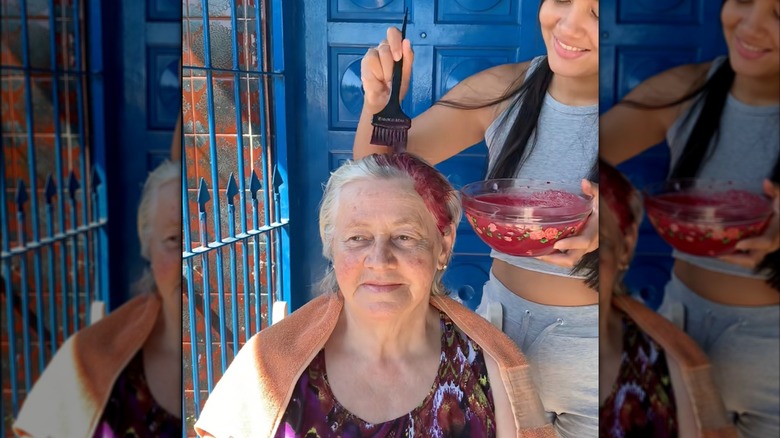 An older woman with gray hair getting a beet mixture put onto her head