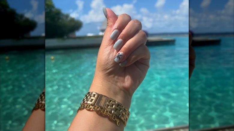 Blue nails with a palm tree accent nail art design.