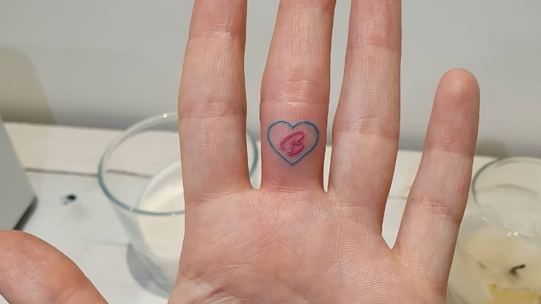 hand with barbie middle finger tattoo