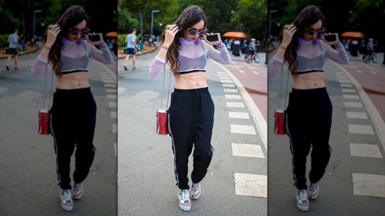 A woman wearing a crop top and track pants