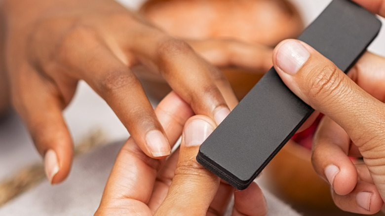 woman filing nails on another woman