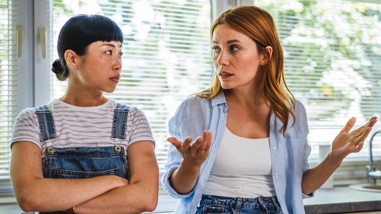 Two women discussing with one showing lack of understanding to the other throuh a shrug