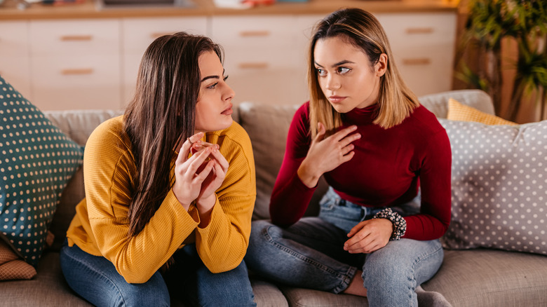 Two women conversaing with one gesturing selfishly to herself