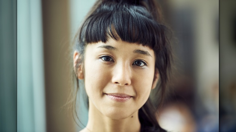 A person with dark hair and short blunt bangs.