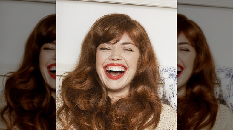 A woman with long voluminous curls smiling