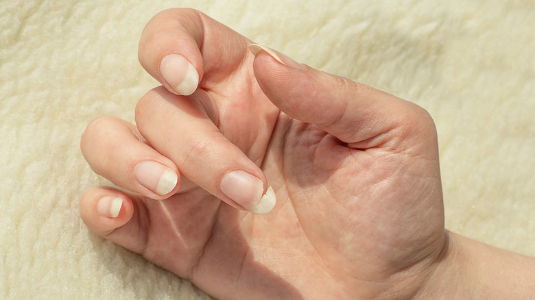 Person's hand with natural long nails and one broken nail