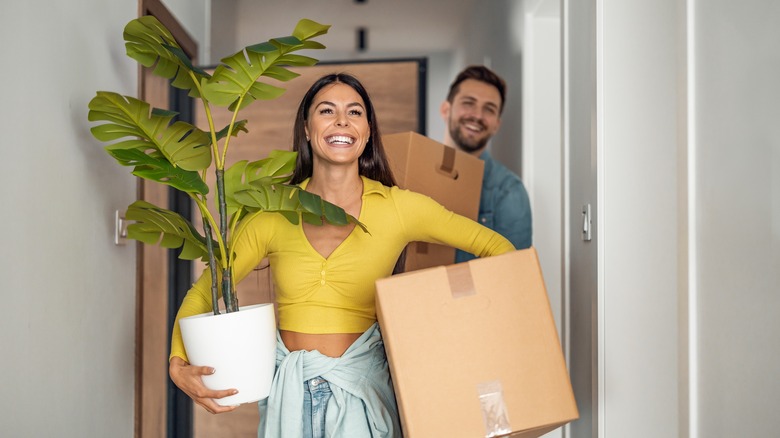 Couple holding moving boxes and plants