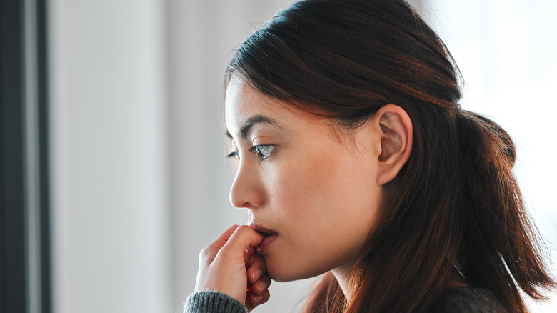 A woman nervously biting her nails.