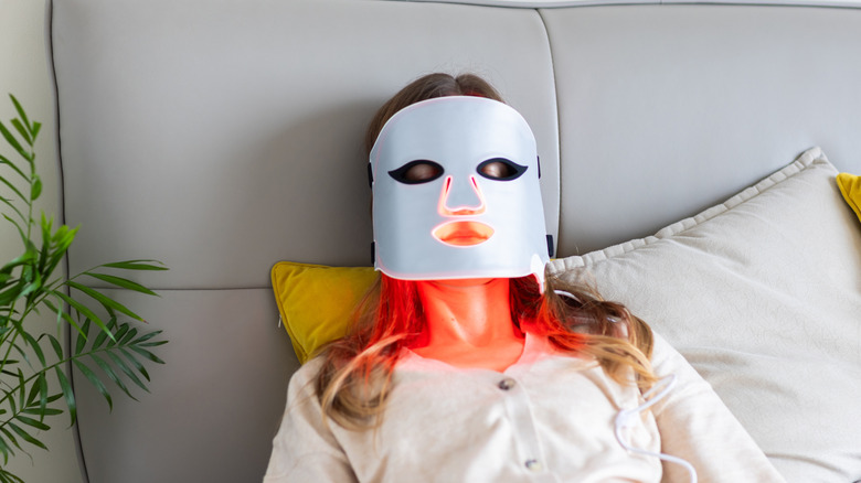 A woman using an LED light therapy mask at home