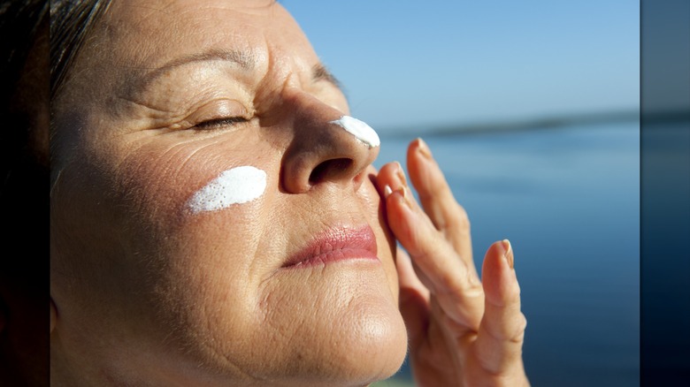 An older woman applying sunscreen while on vacation