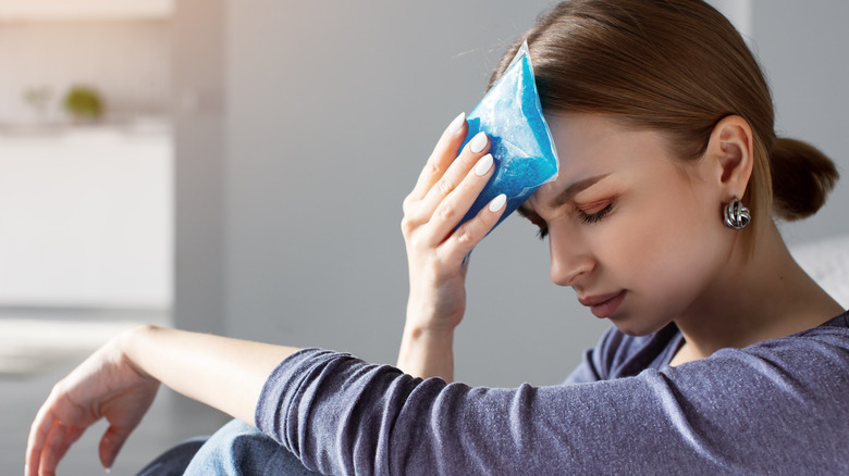 Woman applying cold compress to head