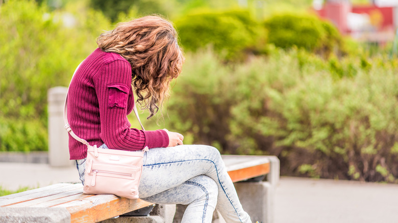 A woman slumping while sitting on a bench