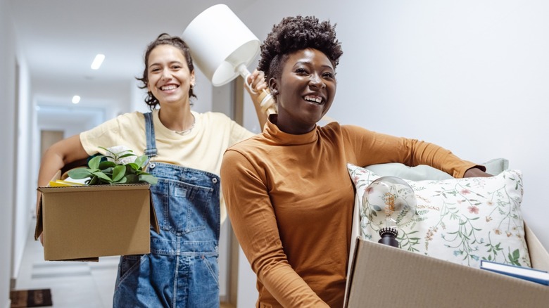 two women carrying stuff and laughing