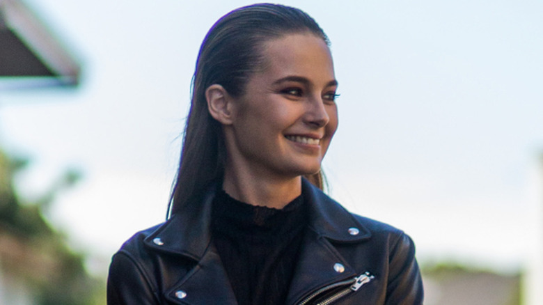 A woman in a leather jacket with her wet-look hair slicked back.
