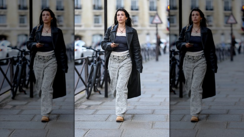 A person walking with gray baggy jeans and a trenchcoat