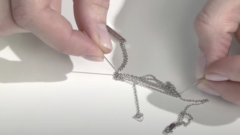 woman removing knot from necklace