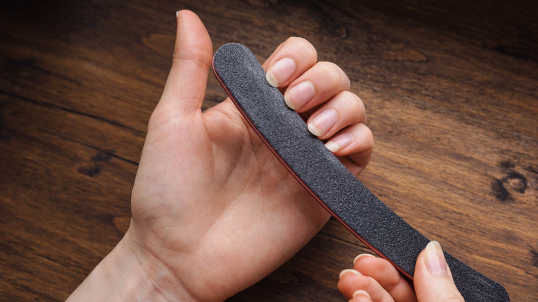 A person filing their nails with an emery board