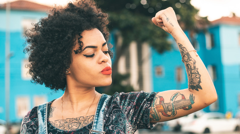 Strong woman flexing tattooed arm