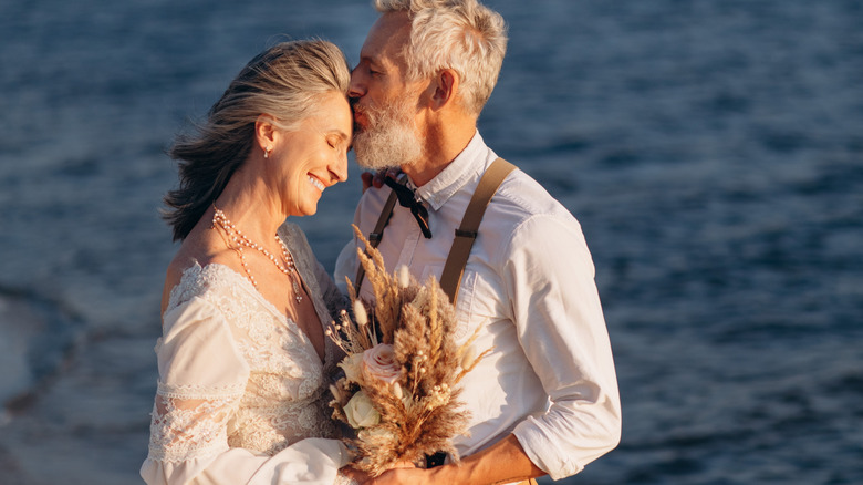 An older bride and groom kissing on their wedding day