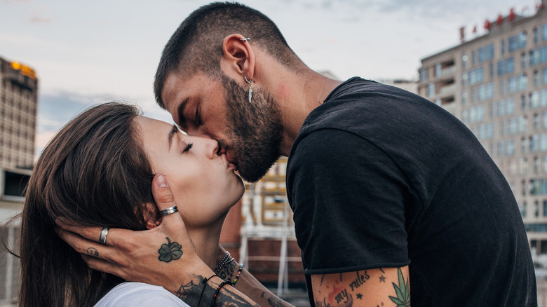 A cool couple kissing in a city.