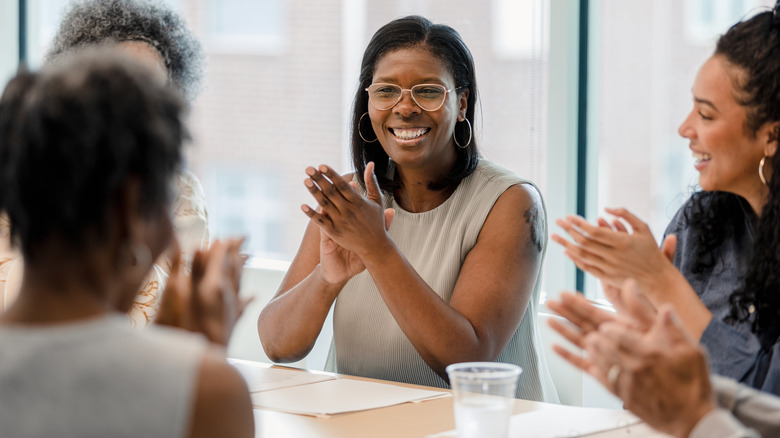 Colleagues clapping around conference table