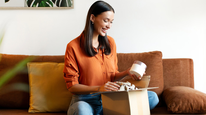 A woman smiles as she unpacks products from a box