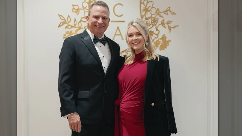 Karoline Leavitt wearing a wine dress posing beside Nicholas Riccio who looks so much older her is in a suit