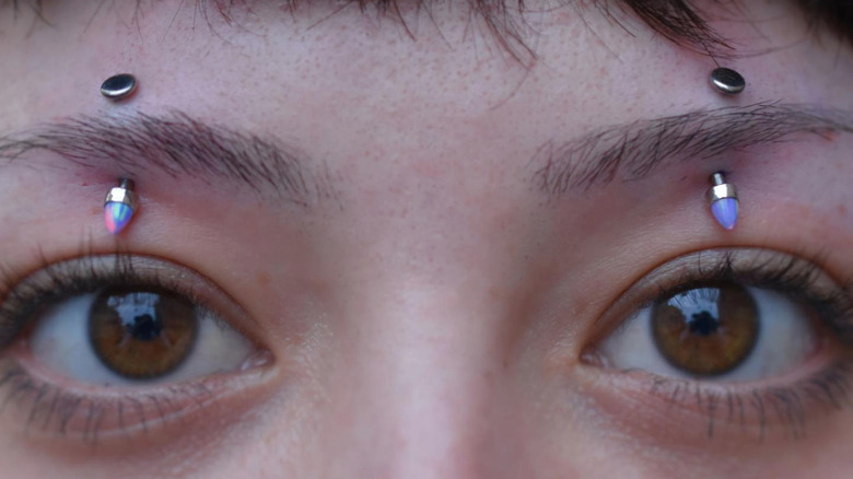 person with double eyebrow piercing