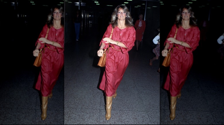 Farrah Fawcett wears a red dress and brown boots