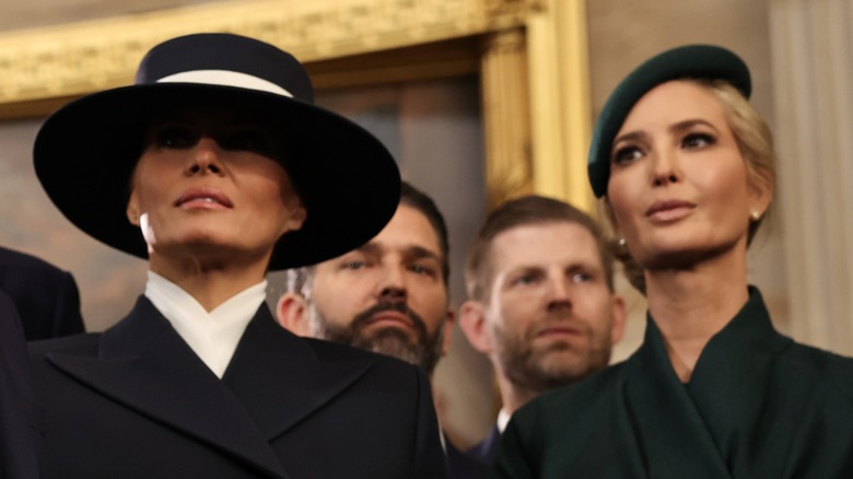 Close-up of Ivanka and Melania Trump. Melania is a glamorous middle aged woman with tanned skin and long dark hair. Ivanka is about ten years younger, with fair skin and blonde hair.