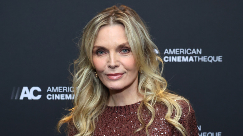 Michelle Pfeiffer wearing a brick-red dress and makeup