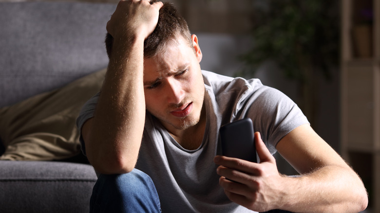 sad man checking phone