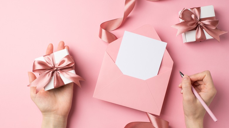 Person holding Valentine's Day gift and writing in card