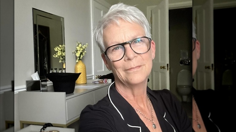 Jamie Lee Curtis wearing black pajamas and black glasses in a selfie.