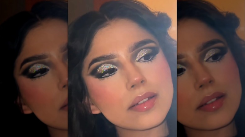 Selfie of woman with glittery eyeshadow and glossy lips.