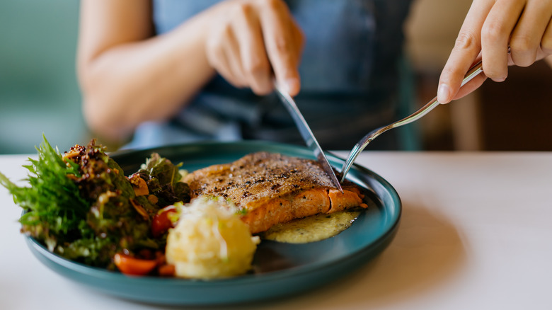 Woman eats salmon and vegetables 