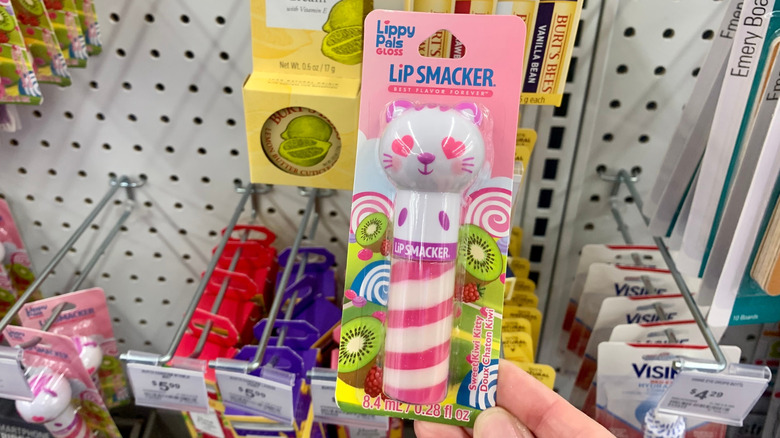 A woman holding up a Lip Smacker product in a store