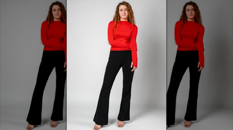 Girl stands tall in long sleeve red shirt and black flare leggings
