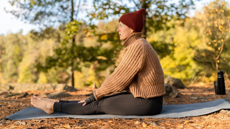 Women wearing leggings sitting on mat in park during autumn