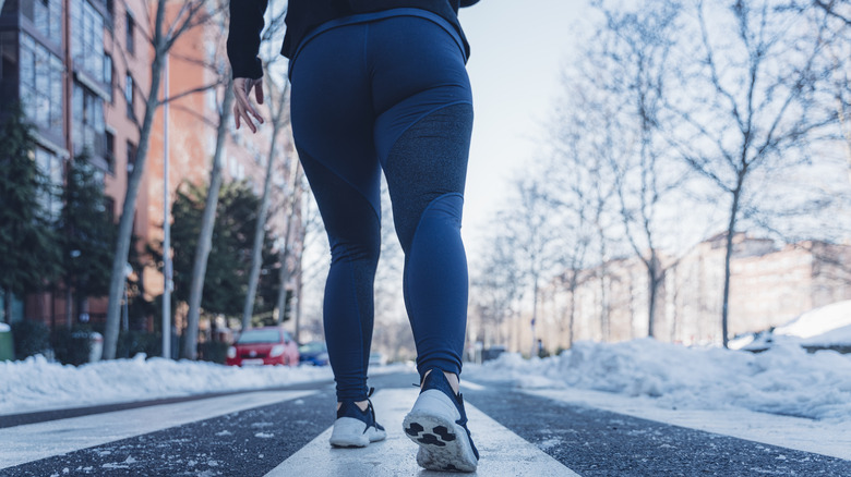 A person wearing warm leggings as they walk outside on a snowy road