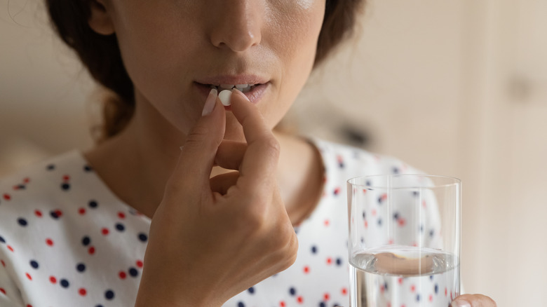 Woman taking medication tablet with water