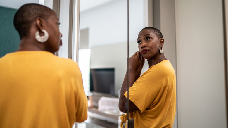 A woman putting on earrings