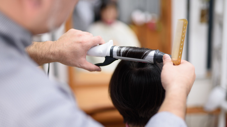 Person curling client's short hair